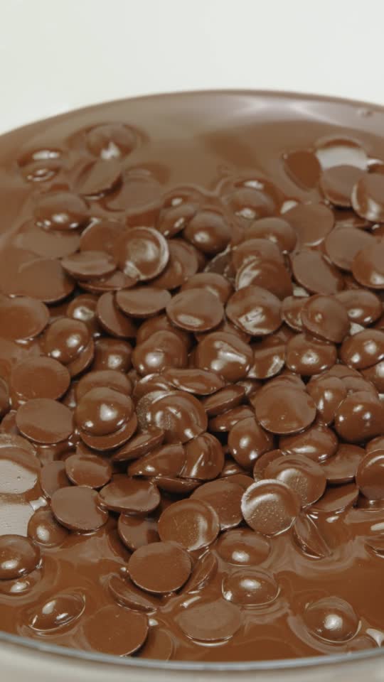 Closeup stirring mixing dark melting chocolate in glass bowl, s Stock