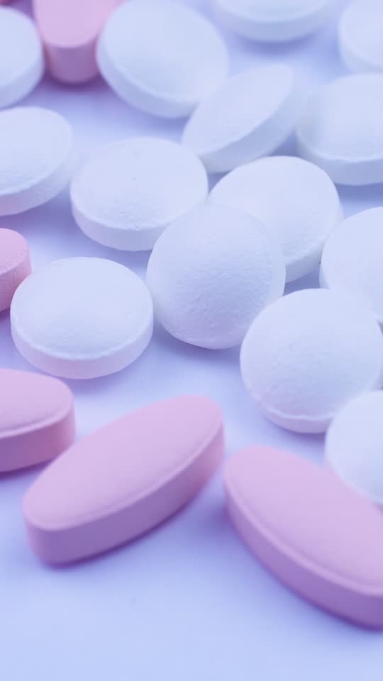 Pink oval tablets are neatly arranged in small white pills. Clo Stock