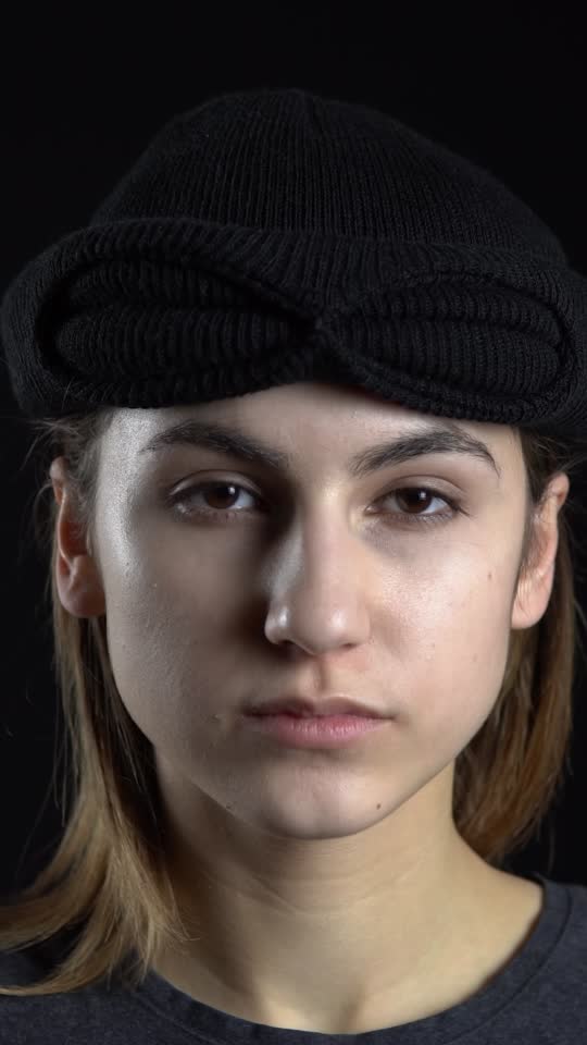 A young woman is putting on a balaclava mask. Bandit on a black Stock